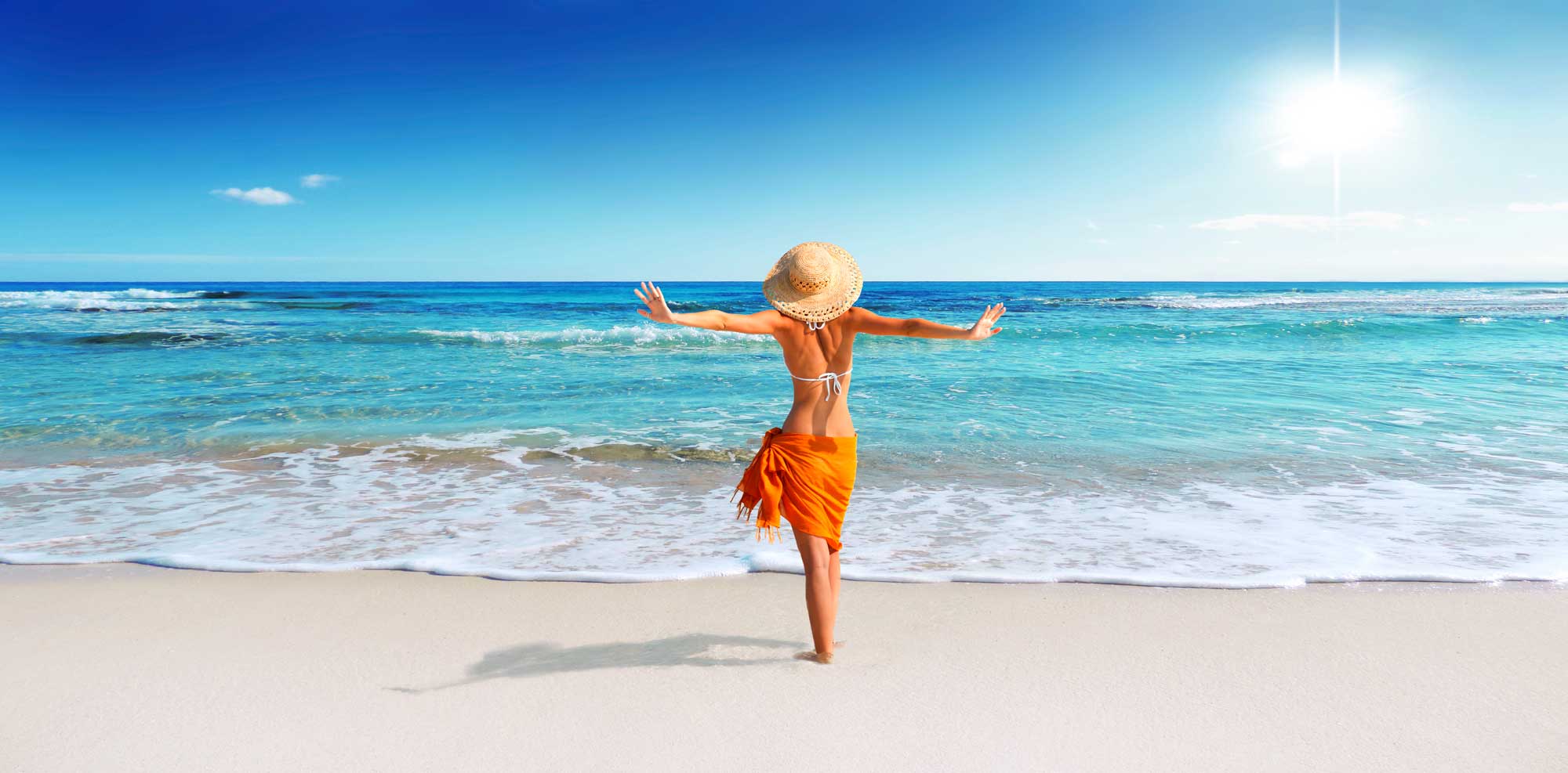 Eine Dame an einem azurblauen Strand am Posieren mit dem Rücken in die Kamera
