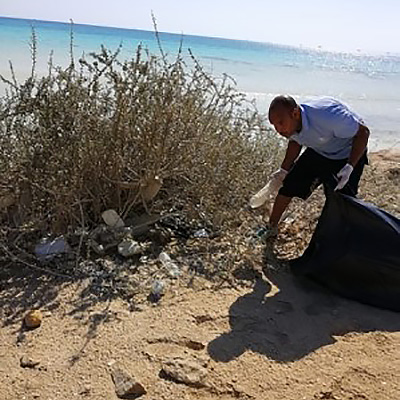 Freiwilliger sammelt Flaschen an einem Hurghada-Strand ein