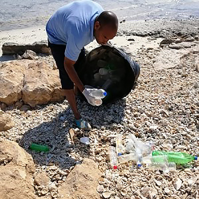 Projekt-Freiwilliger sammelt Plastikflaschen auf einer Insel ein