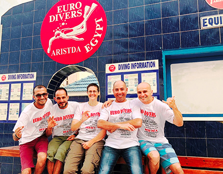 Personal von der Tauchschule Euro Divers zeigt das OK-Zeichen bei einem Gruppenfoto vor dem Lokal