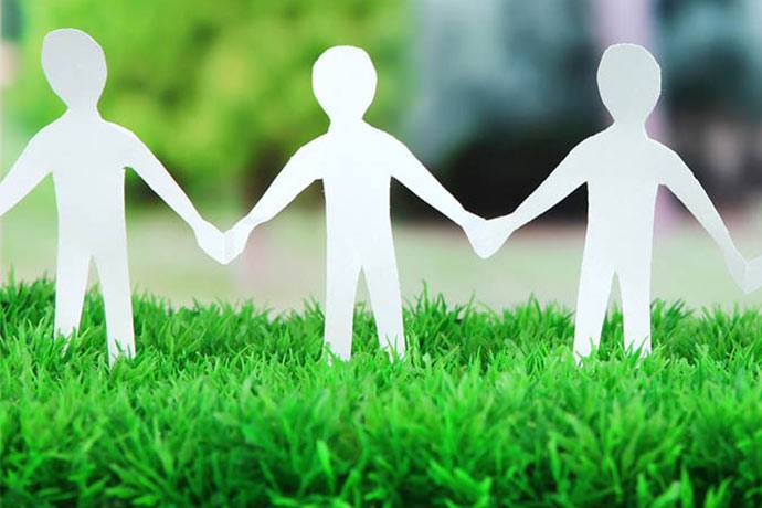 Weiße Papierfiguren auf grüner Wiese