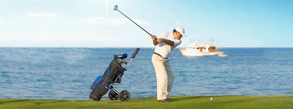 Golfer mit weißer Kleidung schwingt den Golfschläger auf einem Golfplatz in Ägypten