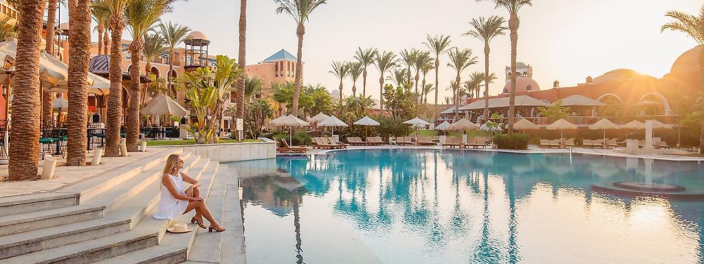 Frau am Pool mit Palmen im Hintergrund