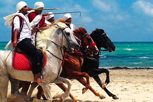3 Männer reiten auf Pferden am Strand vor dem Meer