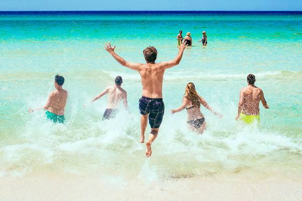 Fünf Urlauber rennen ins Meer und Wasser spritzt auf